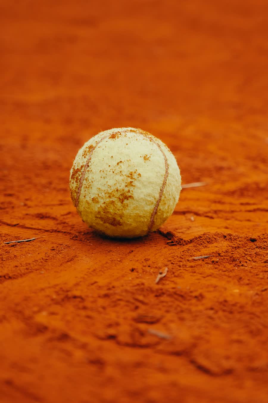 A worn tennis ball left on a clay court